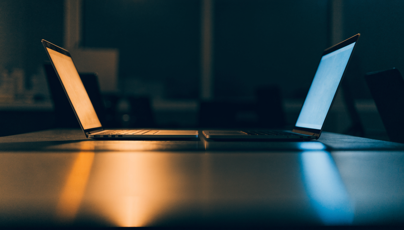 Technician's dual-monitor workbench at night showing email traffic on one screen and DNS records on the other.